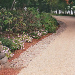 This decorative stone driveway incorporates large river rock on top to disguise an underground drainage system.
