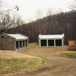 As general contractor, we oversaw and implemented the land clearing, excavation, drainage, fine grating, masonry, garage construction and landscaping of this project. The garages are designed to complement their wooded setting including the natural fieldstone accents. On the right are three custom-designed compost bins.