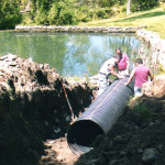 Installing reinforced N12 drainage pipe in an excavated area to create controlled drainage for a private residence to direct run off from the property into a pond.